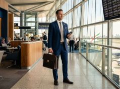 Business Travel: The Complete 2026 Guide to Corporate Travel Management, Costs, and Trends Professional business traveler with briefcase and smartphone in modern airport lounge